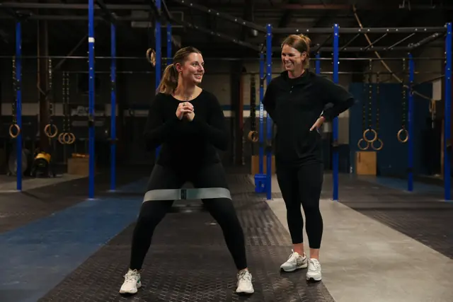 An athlete does banded side steps while Dr. Kiley coaches her