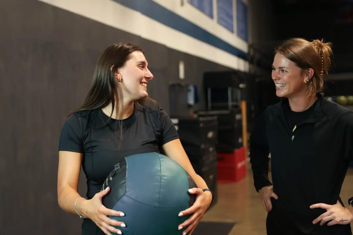 An athlete holds a medicine ball and laughs with Kiley Robb, PT, DPT